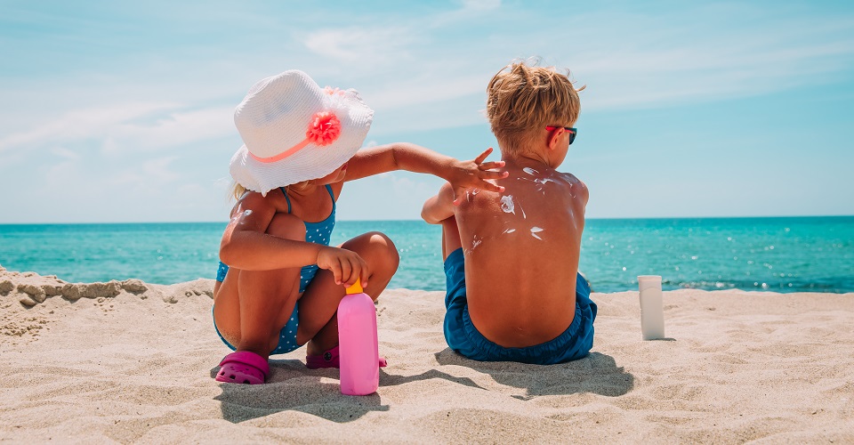 sun protection, little girl applying sunblock cream on boy shoulder