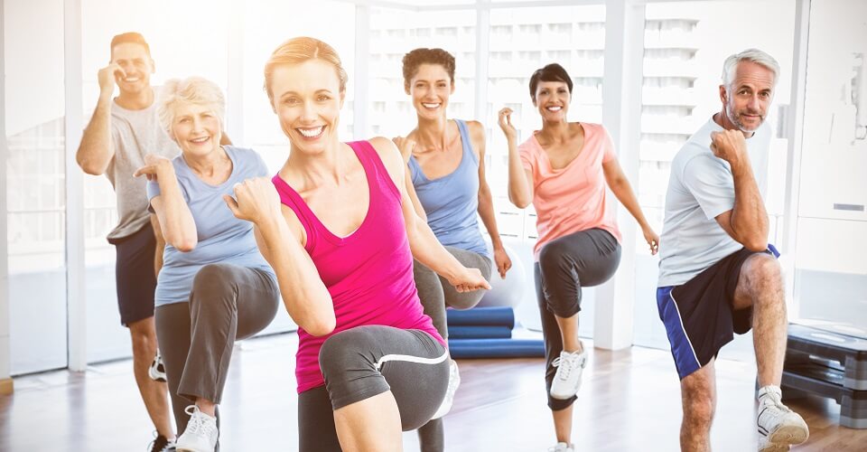 Portrait of smiling people doing power fitness exercise at yoga class in fitness studio